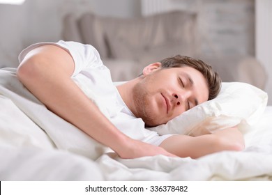 Fast sleep. Good-looking young guy sleeps innocently in his bed before working day officially begins. 