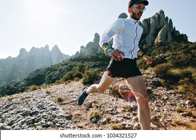 Fast and strong, fit athletic man runs on mountain path or trail during ultra marathon race, hard training workout, healthy lifestyle choice to spend time outdoors in nature in national park