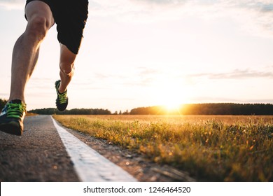 Fast Strong Runner Feet Running On Asphalt Road Close Up In Sport Shoe. Athlet Run Outdoor. Blurred Background