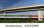 fast train going really fast through a lovely summer landscape and under a highway bridge
