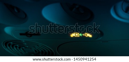 Fasten your seat belts blinking icon announcement on small air plane night flight or when flying in turbulences area. Blurry yellow green Buckle up sign on dark black blue airplane interior background