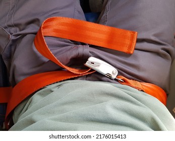 Fastened Orange Seat Belt On The Passenger In The Plane