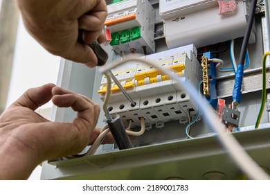 Fastening circuit breakers to DIN rail of consumer unit of electrical panel. Mounting fuse box for distribution board. - Shutterstock ID 2189001783
