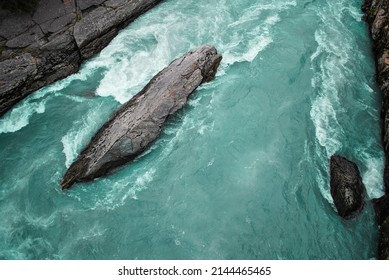 Fast-flowing aqua-colored River in Loom Norway, creating white water around gray rocks. 