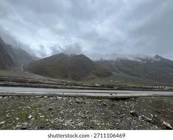 A fast-flowing river winds through a deep, steep-sided, and rocky mountain gorge under a partly cloudy sky.
