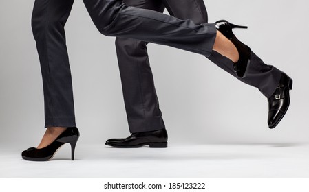 Fast-paced business: male and female legs running on grey background