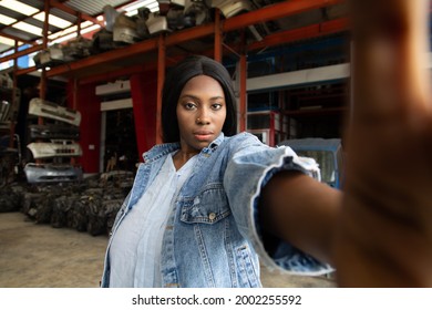 Fat African American Woman Modeling Making Selfie Camera Photo. Old Machine Auto Parts In Warehouses. Auto Mechanic Car Service, Repair And Maintenance Concept.