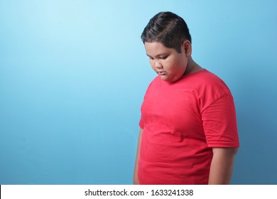 Fat Asian Boy Looking Down, Sad And Crying, Being Bullied, Sadness, Child Abuse Concept, Against Blue Background