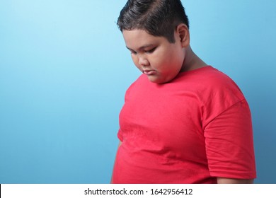 Fat Asian Boy Looking Down, Sad And Crying, Being Bullied, Sadness, Child Abuse Concept, Against Blue Background