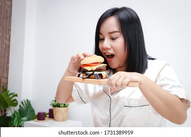 Fat Asian Woman Eating A Hamburger. Full Of Things That Cause Diabetes, Heart Disease, Obesity And Liver Disease. Junk Food Concept