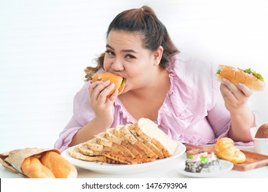 Fat Asian woman sitting and eating hamburger, plus size model hold hamburger in 2 hands cakes and look at camera, Happy woman likes to eat