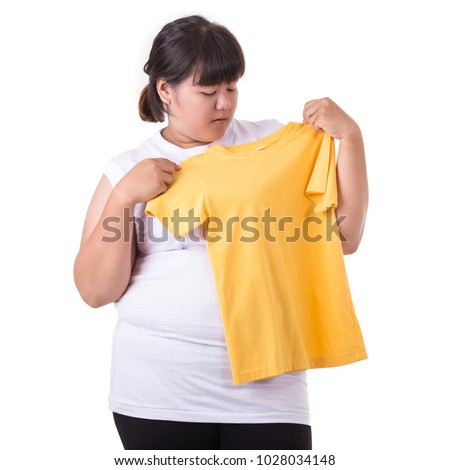 Fat asian woman trying to wear small size of yellow t-shirt isolated on white background. Fat and Healthcare concept