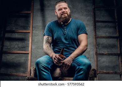 Fat bearded man drinking beer from a bottle.