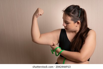 Fat beautiful woman pulls cellulite under her arms with a measuring tape. excess fat under the arms. healthy weight control concept