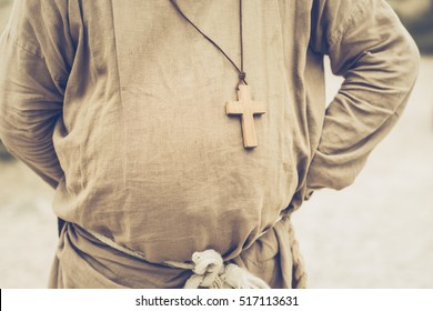 Fat Belly Of A Priest / Monk / Pope Hiding His Hands Behind His Back, With A Wooden Cross