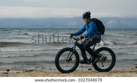 Fat bike also called fatbike or fat-tire bike in summer driving on the beach. The guy is going straight on the beach. On the sand on such a bike ride is not difficult. Stock photo © 