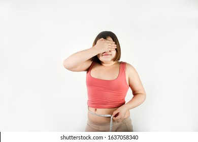 fat chubby kid girl with centimeter tape measures waist volume of abdomen, sadness and surprise. Children obesity concept, overweight control. White background