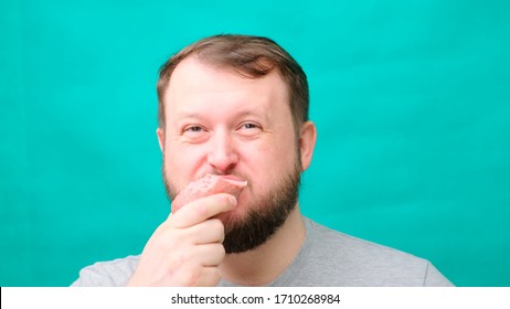 A fat chubby man with a beard eats sausage or meat, a concept of harmful unhealthy lifestyle