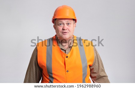 fat construction worker in funny confusion in hard hat and reflective vest, bulder does not understand and fooling around showing comic face expression