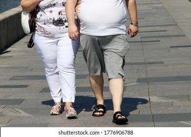 Fat couple walking along a summer street. Concept of overweight, body positive, hot weather in city