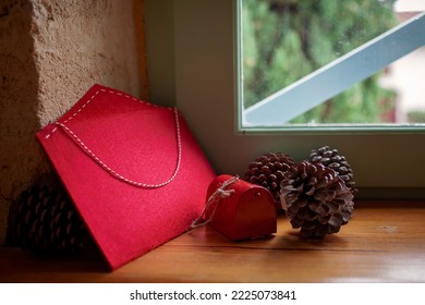 A fat envelope for letters to Santa Claus, large beautiful fir cones and a small decorative mailbox as Christmas decor lie on the windowsill in an old house. Seasonal holiday is coming