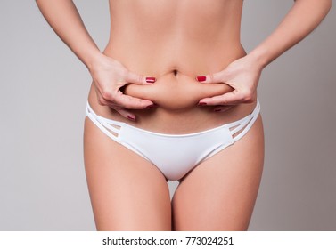 Fat female belly, woman holding her skin for cellulite check. Getting rid of belly fat and weight loss