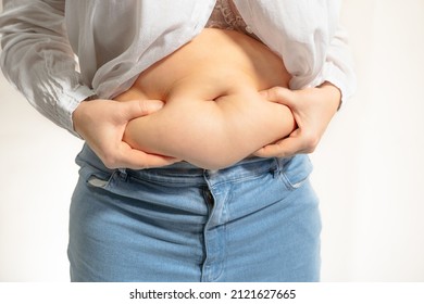 Fat Figure Of Woman With Folds Of Fat On Stomach, No Waist, Presence Of Cellulite, Overweight. Woman With Bare Belly, Wearing Small Size Jeans And White Shirt With Fat Belly. 