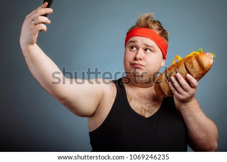 Fat funny man with sandwich in hand makes selfie
