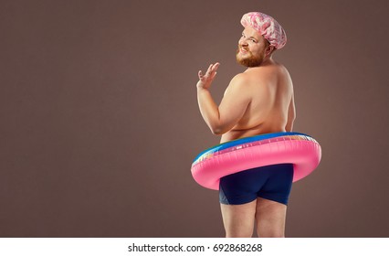 Fat funny man in a swimsuit with an inflatable circle. 