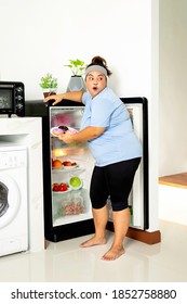 Fat Girl Sneak And Taking Donuts Out From The Refrigerator In Concept Failed Lose Weight Diet. Unhealthy And Healthy Food.