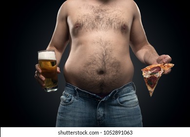 fat guy in jeans holding a beer and pizza on a dark background
