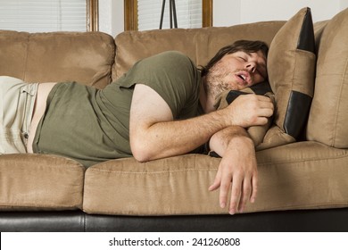 Fat guy sleeping on the couch in what looks like an uncomfortable position