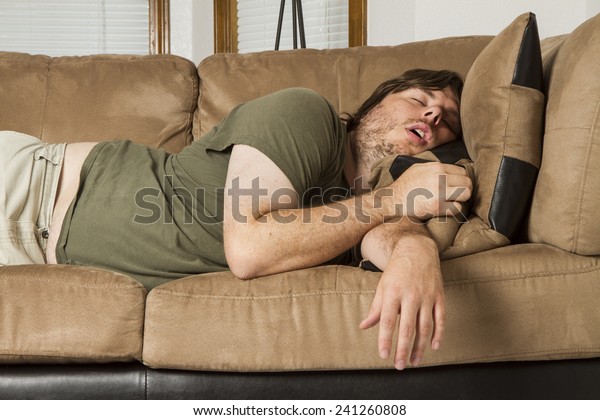 Fat guy sleeping on the couch in what looks like
an uncomfortable position