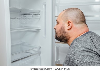 Fat Hungry Man Is Looking For A Food Into Empty Fridge.