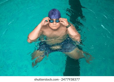 Fat male swimmer adjust goggles in swimming pool, water sports concept - Powered by Shutterstock