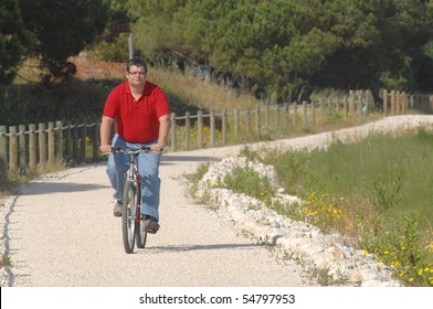 Fat Man Cycling On The Countryside Making Exercise