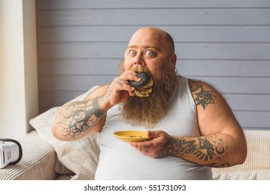 Fat man eating unhealthy burger at home