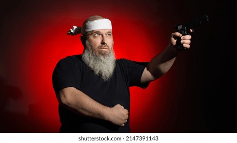 A Fat Man With A Gray Beard And A Bandage On His Head Aims With A Gun On A Dark Background