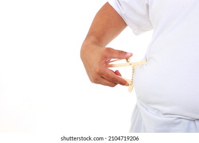 Fat Man Holding A Caliper To Measure The Amount Of Fat In His Stomach Used To Measure The Thickness Of The Fat Layer. White Background. Weight Loss Concept.