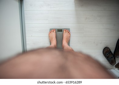 Fat Man Measuring His Weight On A Scale