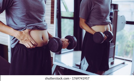 Fat Man, Obese Man Hand Holding Excessive Belly Fat Isolated On Gym Background, Overweight Fatty Belly Of Man, Man Diet Lifestyle Concept To Reduce Belly And Shape Up Healthy Stomach Muscle.