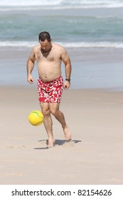 A Fat Man Playing With A Ball On The Beach