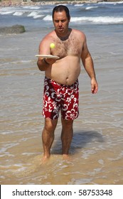 a fat man playing beach tennis on the beach