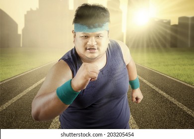 Fat man running for exercising on racing track