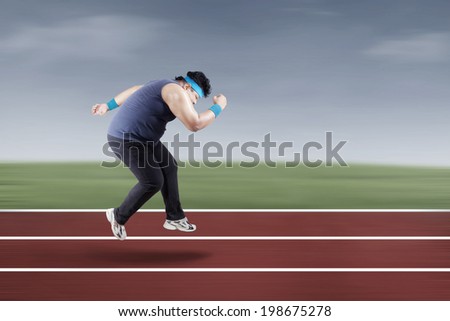 Fat man running for exercising on racing track