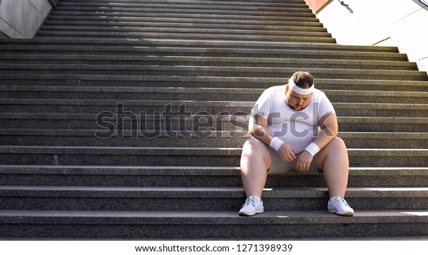 ジョギングの後階段に座っている太った男は 自分を信じず 不安を抱いている の写真素材 今すぐ編集