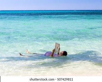 Fat man in swimsuit lying in the sea and reads newspaper. Funny man in retro swimsuit floats on his back in the sea, reading news. Relax with newspapers at tropical sea.Holidays in exotic destination.