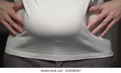 Fat Man. Man Touches His Stomach. Belly, Overweight. Oversize Person In A White Shirt Holds Skin. Slimming Diet, Liposuction And Unhealthy Lifestyle. Bold Male Waist.