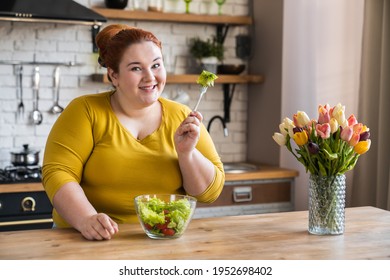 Fat Obese Plump Young Caucasian Woman Eating Salad For Healthy Diet And Eating Habits In The Kitchen. Chubby Plus Size Woman Having Salad For Breakfast