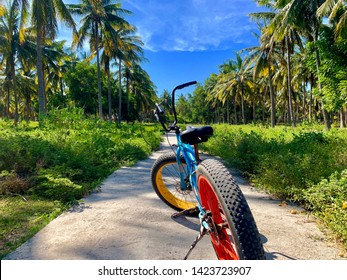 Fat sand tire bicycle on a tropical road lines with coconut forest, shot in Gili Trawangan, Bali, Indonesia.